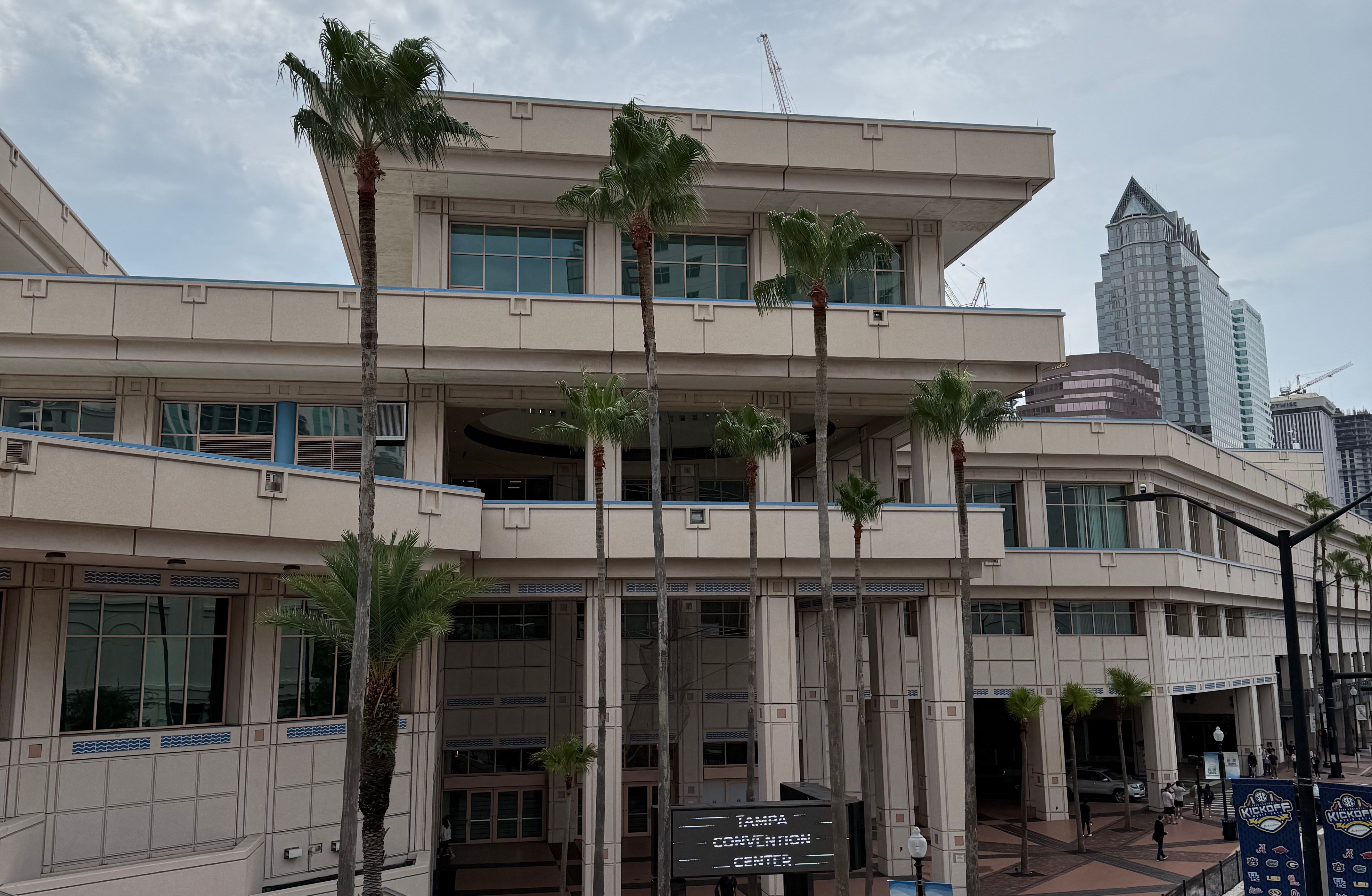 Tampa Convention Center fronted by tall palm trees with the downtown Tampa skyline behind it